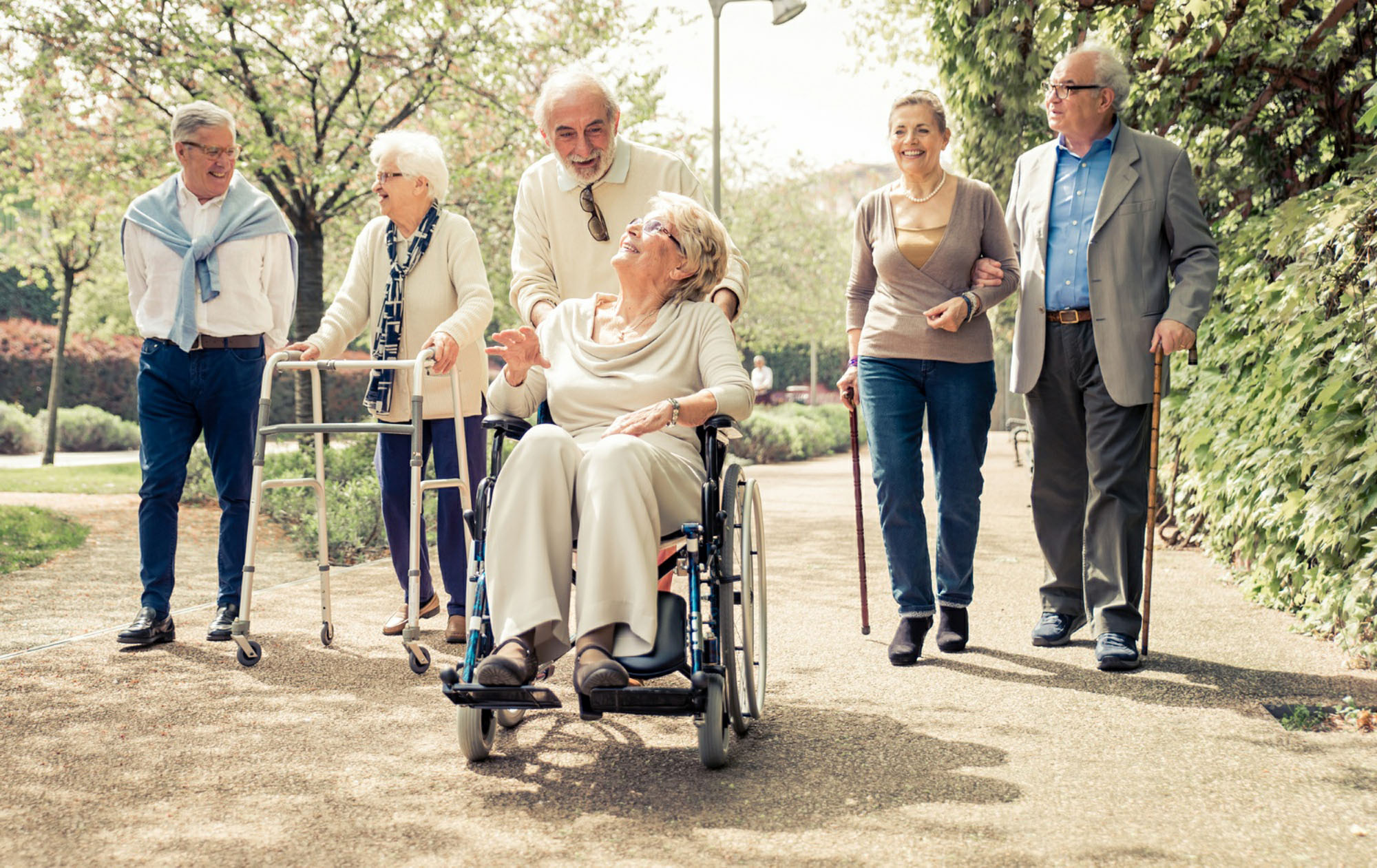Group of diversely-abled older adults enjoying a walk in the park.